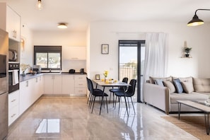 A modern kitchen with a dining area, a sofa, and a balcony. - MAMAD - Stella Maris views Vista apartments by Sea N' Rent (Haifa)