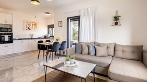A modern living room with a sofa, a coffee table, and a dining area with chairs and a table. - MAMAD - Stella Maris views Vista apartments by Sea N' Rent (Haifa)