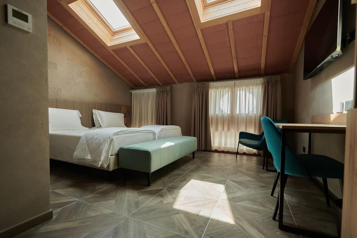 Une chambre à coucher avec un lit, un bureau et une chaise. Il y a des fenêtres de toit au plafond.