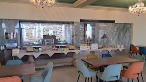 A restaurant with a marble counter, colorful chairs, and a chandelier. - Parc Hotel San Pietro  (Caprino Veronese)