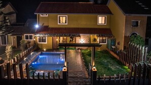 A two-story house with a swimming pool, a covered patio, and a fenced yard. - Stone Shelter (Mahabaleshwar)