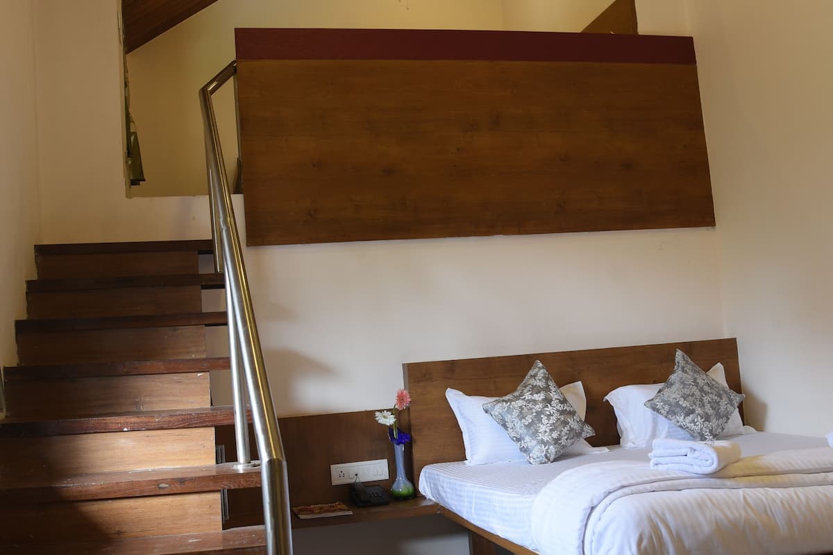 A bedroom with a wooden bed, a wooden staircase, and a sloped ceiling.
