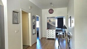 Ein geräumiger Korridor mit Holzboden, einer Chandelüster und einem Essbereich mit Tisch und Stühlen.