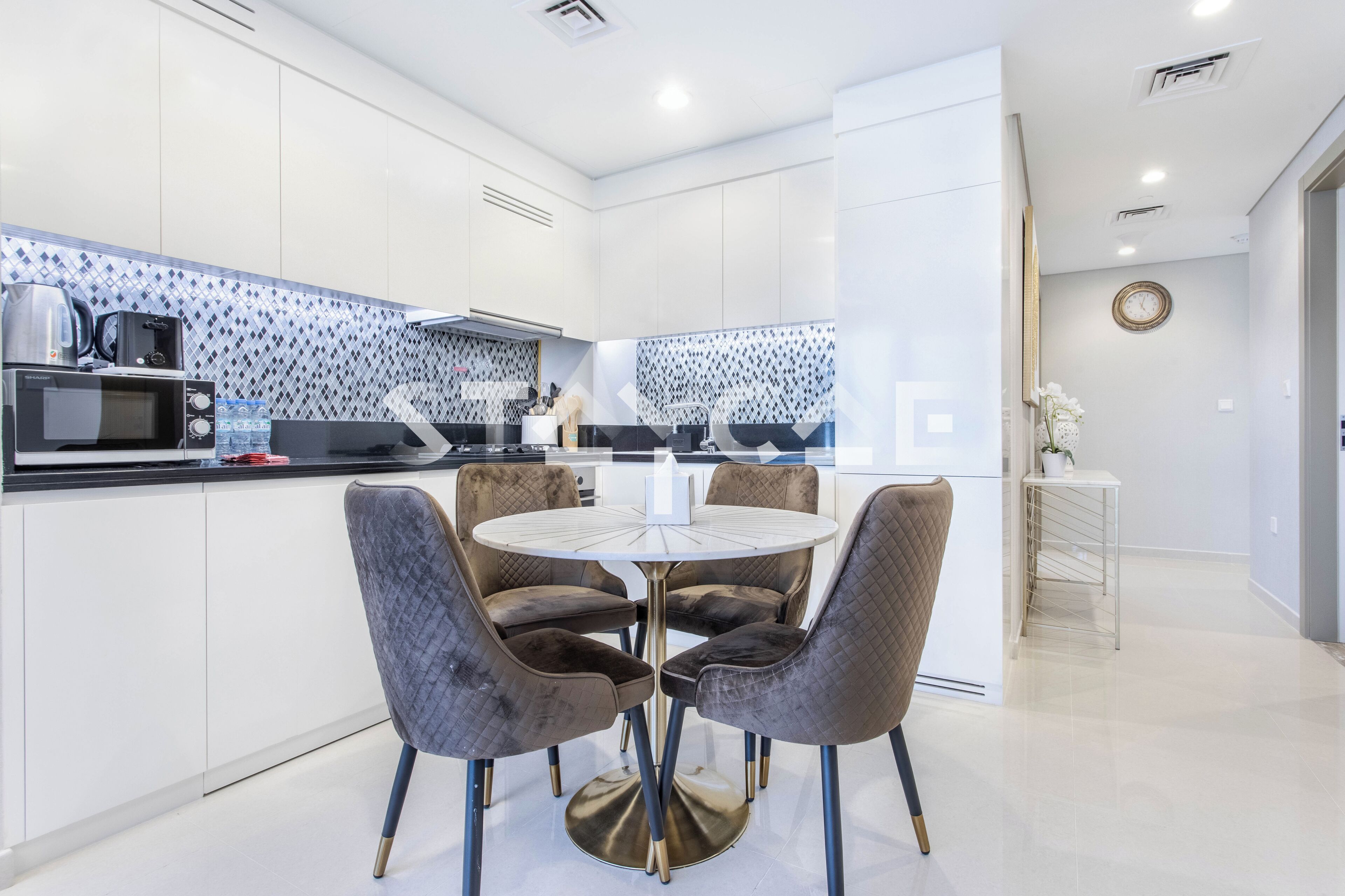A modern kitchen with white cabinets, a black countertop, and a round table with four chairs.