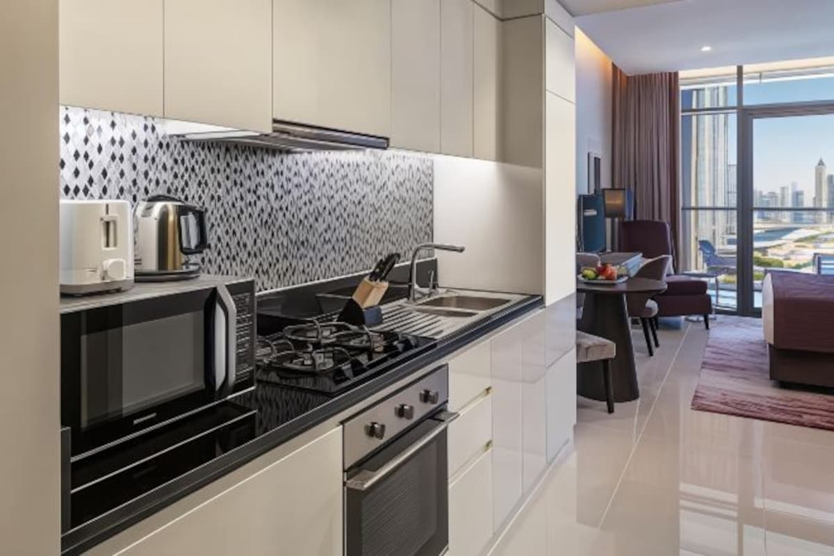 A modern kitchen with a gas stove, microwave, and kettle, and a dining area with a table and chairs.