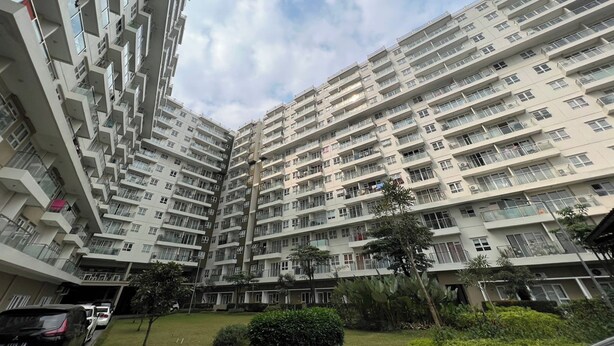 Een hoog appartementencomplex met meerdere balkons, een binnentuin en veel groen eromheen.