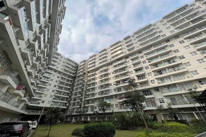 Een hoog appartementencomplex met meerdere balkons, een binnentuin en veel groen eromheen.