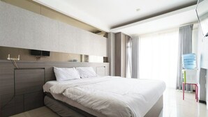 Een moderne hotelkamer met een groot bed, een flatscreen televisie aan de muur en uitzicht op het omliggende landschap.