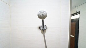 Een douchekop bevestigd aan een betegelde muur.