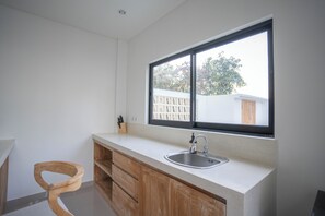 A modern kitchen with a large window, wooden cabinets, and a stainless steel sink.