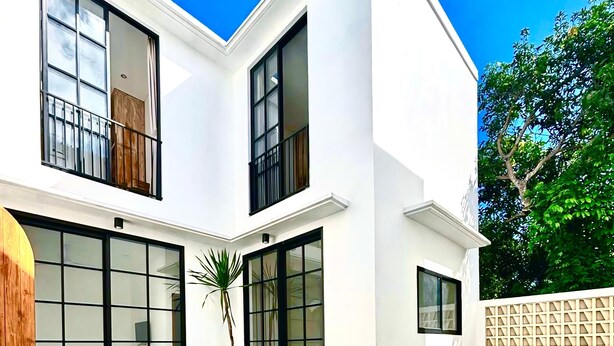 Una casa moderna de dos pisos con piscina, ventanas amplias y césped cuidado.