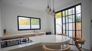 Una cocina moderna con una isla central, sillas de madera y un gran ventanal que ofrece vistas al exterior.