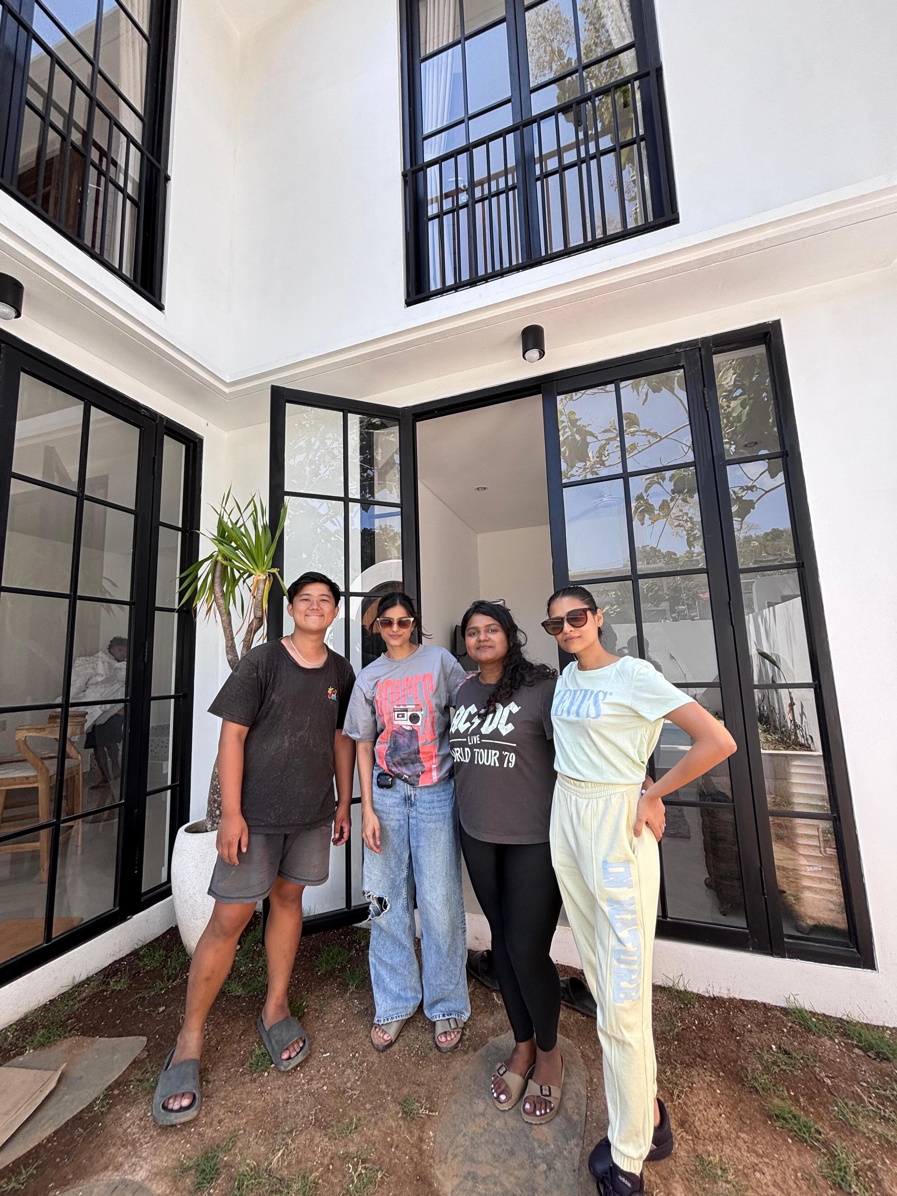 A group of people standing in front of a building with large glass doors and windows.