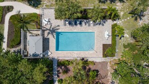 An aerial view of a resort with a central swimming pool, lounge area with sunbeds, and surrounding tropical vegetation. - Exclusive Sanibel Marina Residence with Pool (Sanibel)