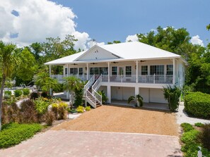 A two-story house with a covered porch, a staircase, and a driveway. - Exclusive Sanibel Marina Residence with Pool (Sanibel)