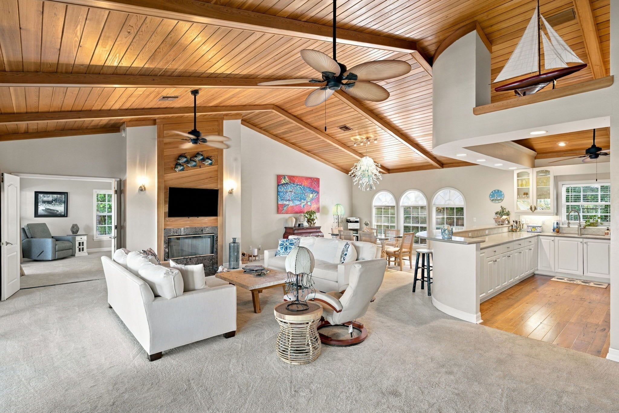 A spacious living area with a fireplace, a dining area, and a kitchen with white cabinetry.