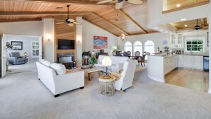 A spacious living area with a fireplace, white furniture, and a kitchen with white cabinets. - Exclusive Sanibel Marina Residence with Pool (Sanibel)