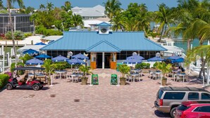 A beachfront hotel with a blue roof, outdoor seating with umbrellas, and a golf cart. - Exclusive Sanibel Marina Residence with Pool (Sanibel)