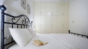 Ein ordentlich bezogenes Bett mit einem Buch darauf, einem weißen Kopfkissen und einem schwarzen Metall-Kopfteil.