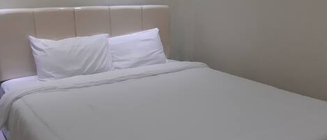 A bed with white bedding and a headboard.