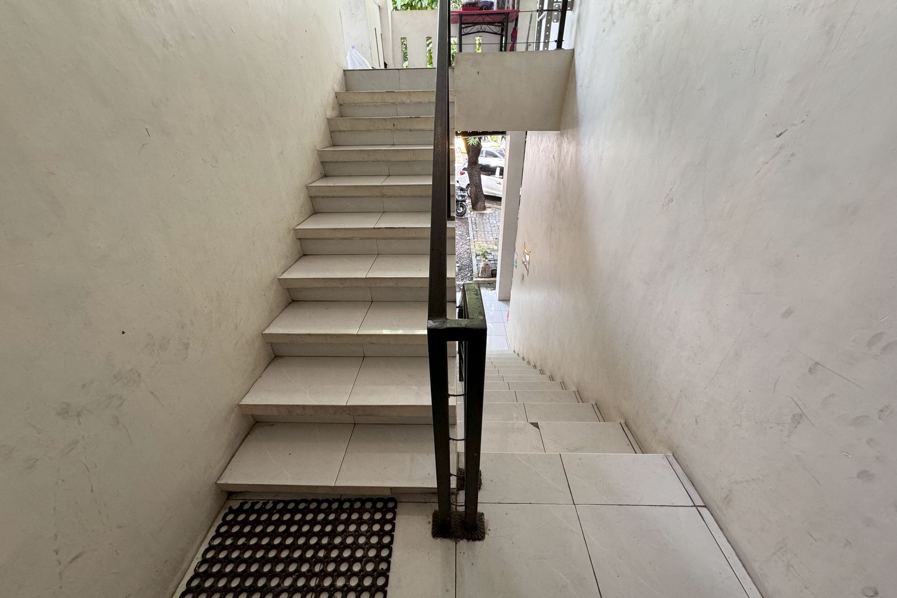 Un escalier muni d’une rampe et d’une grille métallique en bas.