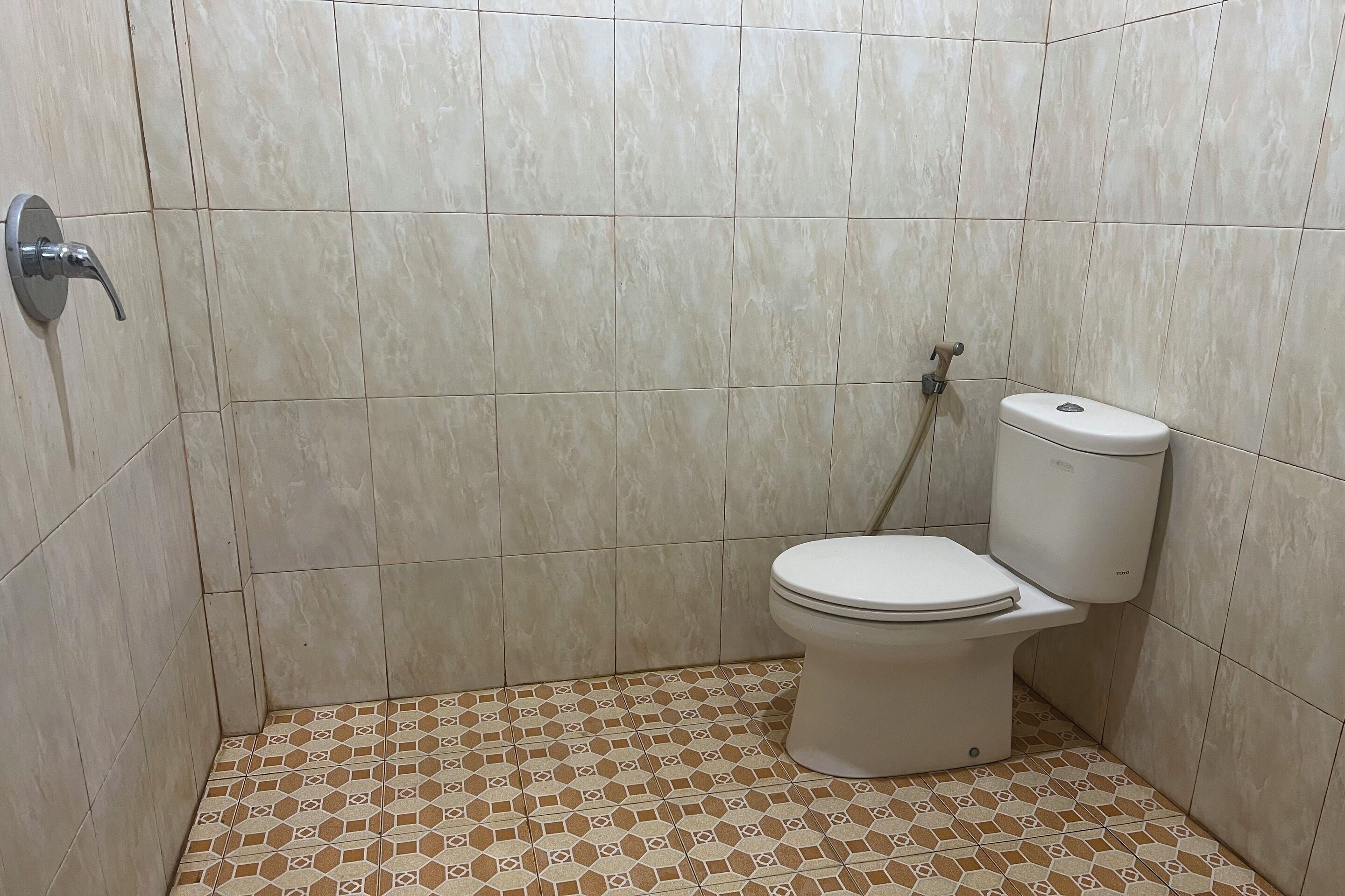 A bathroom with a toilet, a shower, and tiled walls.