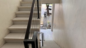 Un escalier avec une rampe noire menant à un espace extérieur.