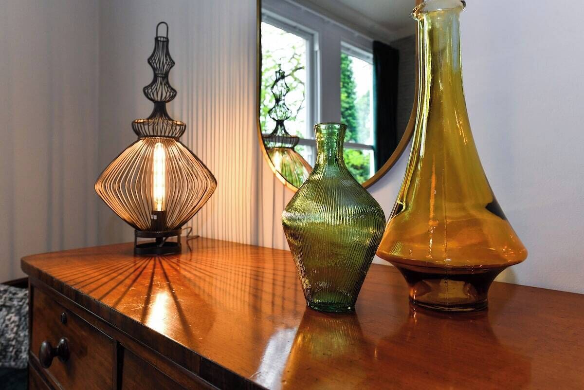Een houten dressoir met drie glazen vazen en een lamp.