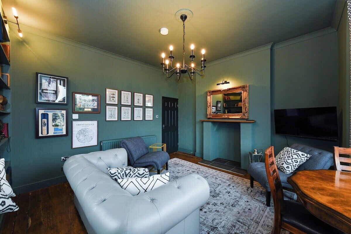 Een woonkamer met een bank, fauteuils, een eettafel en een open haard.
