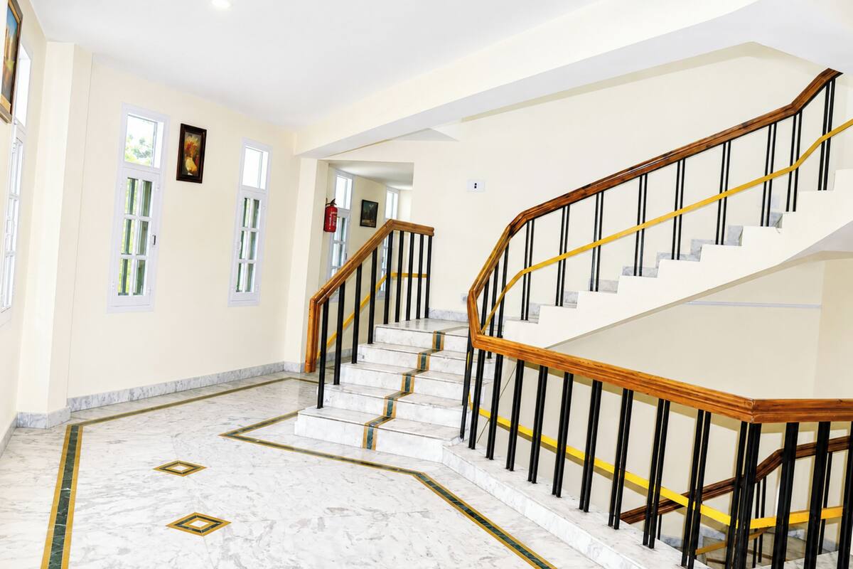 A marble-floored hallway with a staircase featuring wooden handrails and black balusters.