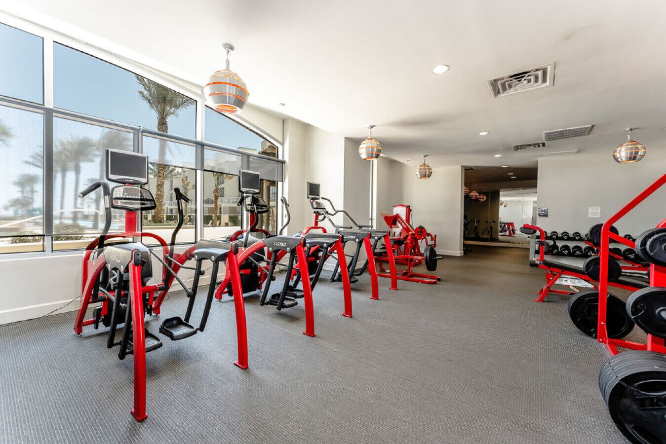 A gym with treadmills, elliptical machines, and a rack of dumbbells.