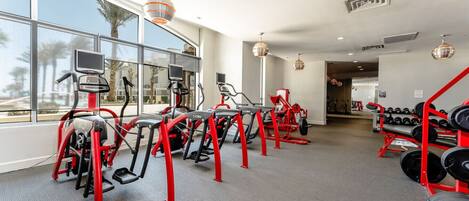 A gym with treadmills, elliptical machines, and a rack of dumbbells.
