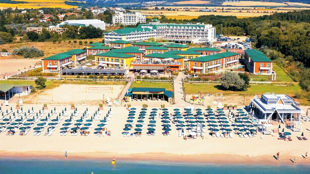 A coastal hotel with multiple buildings, a beach with rows of umbrellas, and a clear view of the sea. - Therma Palace - Hotel & SPA (Kranevo)