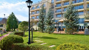 A hotel with a garden, a lamp post, and a building with multiple balconies. - Therma Palace - Hotel & SPA (Kranevo)