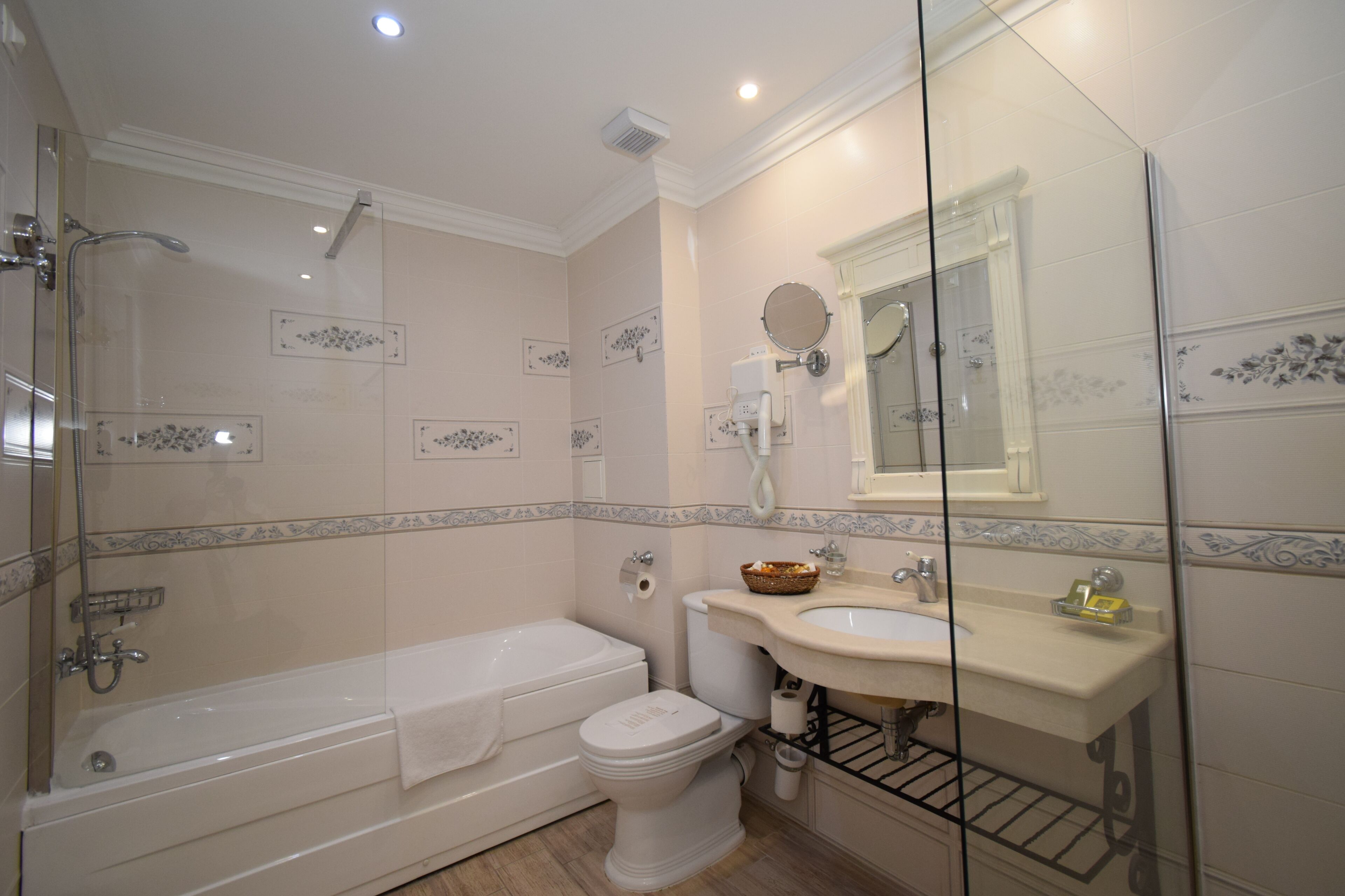 Un baño con ducha de vidrio, bañera, inodoro e lavamanos con espejo.