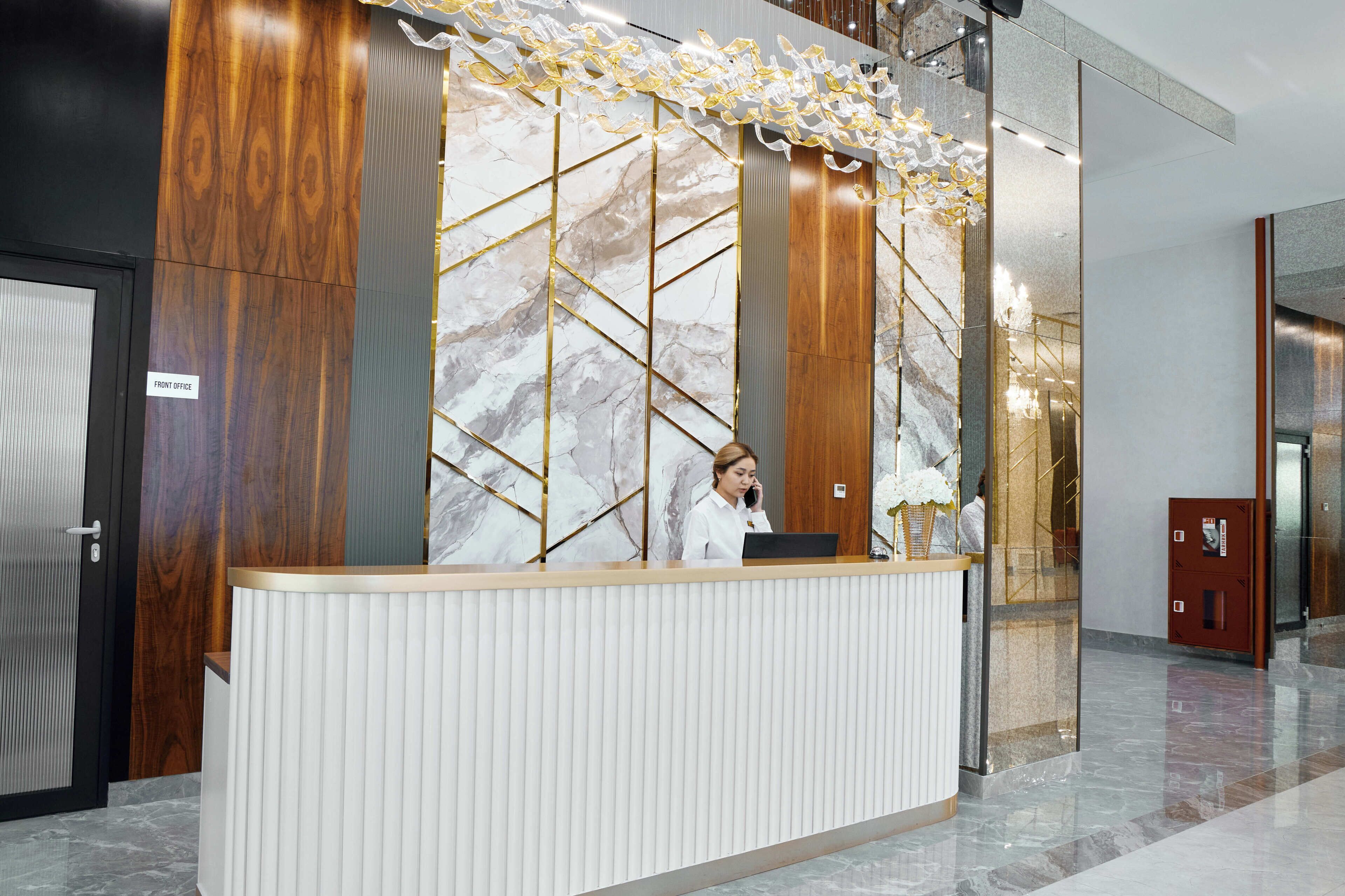 Una recepción con un muro de mármol, un panel de madera y una lámpara moderna.