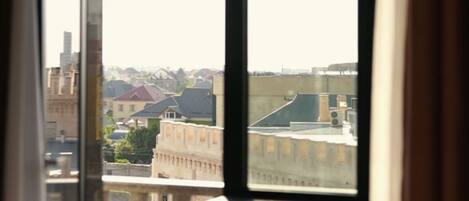 A room with a large window, a radiator, and a view of buildings outside.