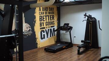 A gym with a treadmill, weight bench, and a wall with motivational text.