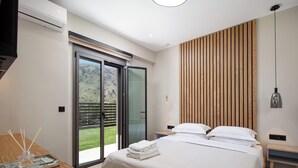 Une chambre moderne avec un grand lit, un mur recouvert de panneaux en bois, une porte-fenêtre coulissante donnant sur un balcon et une table de chevet avec une lampe.