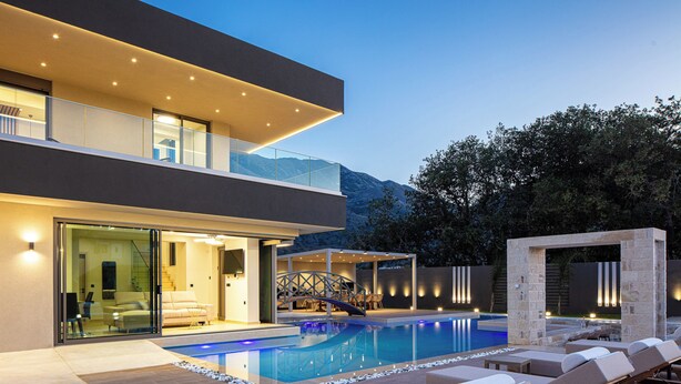 Une maison moderne dotée d’une piscine, d’un espace salon extérieur et offrant une vue sur les montagnes.