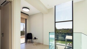Un intérieur moderne avec une cloison en verre, une porte donnant sur un espace extérieur et une petite table avec une chaise.