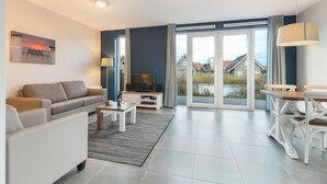 A modern living room with a sofa, TV, and dining table.