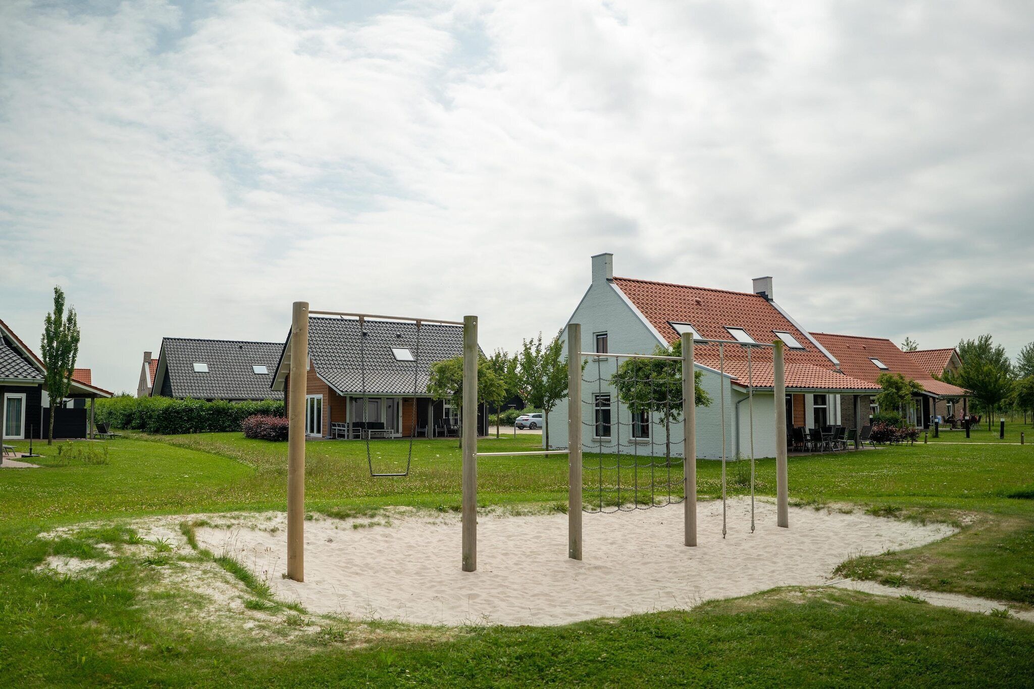 A residential area with houses, a playground, and a sandy area.