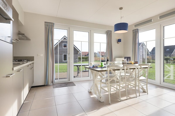 A modern kitchen with a dining area, large windows, and a view of the neighborhood.