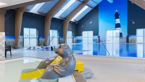 Une piscine intérieure agrémentée d’une sculpture réaliste d’un phoque dans l’eau, de poutres en bois et d’une fresque représentant un phare.