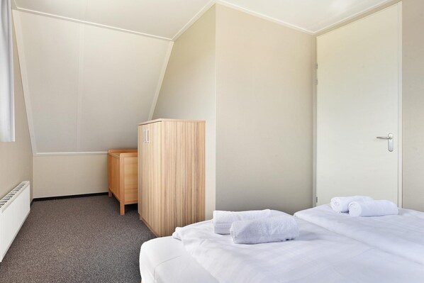 Una habitación de hotel con cama, armario de madera y radiador.