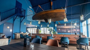 Un intérieur moderne avec une table en bois, des chaises bleues et un coin salon doté de canapés orange.