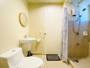 A bathroom with a toilet, sink, shower, and a door. - Avida Riala Towers by P&J (Cebu City)