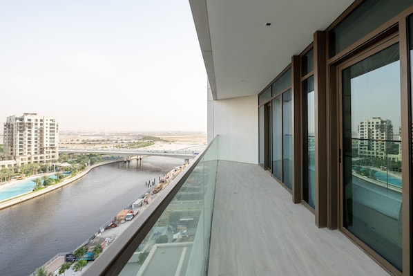 A modern balcony with a view of a river, a bridge, and surrounding buildings.