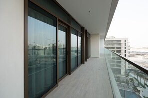 A modern balcony with large glass doors and a view of a cityscape.